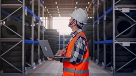 Side View Of Asian Male Engineer Working On A Laptop at Tire Warehouse Stock Footage 341786708