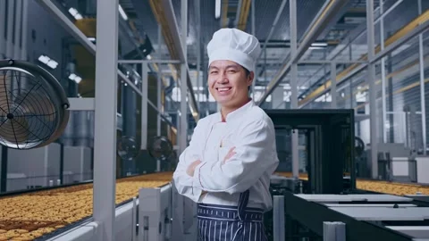 Side View Of Asian Man Chef Smiling And Crossing His Arms In Cookie Factory Vidéo 318080543