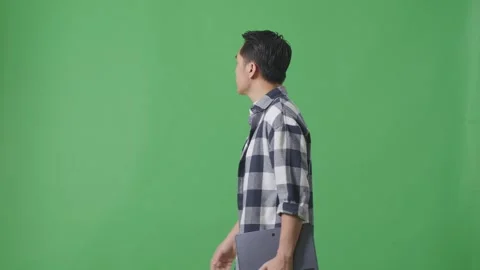 Side View Of Asian Man Holding Tablet While Walking On Green Screen 스톡 동영상 248007870