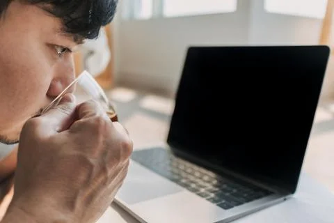 Side view of asian man using computer, lying on floor while working on laptop Foto stock