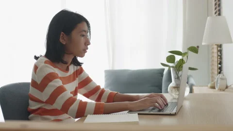 Side view of Asian woman using laptop or typing work at home Stock Footage 157996012