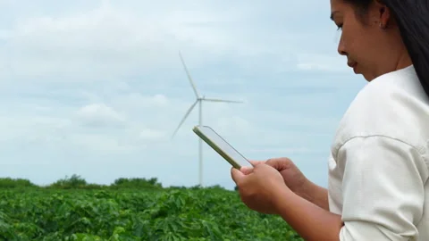 Side view of Asian woman using mobile phone outdoors with wind turbine backgroun Video stock 342906031