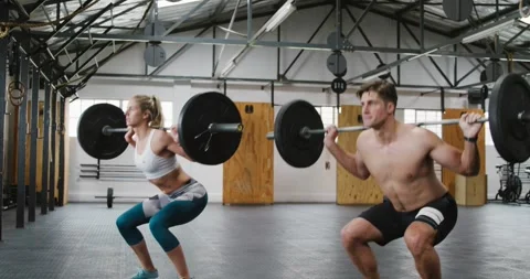 Side view of an athletic Caucasian man and woman squatting Stock Footage 338324915