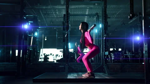 Side view of athletic woman doing barbell back squat in dark illuminated gym Stock Footage 239769031