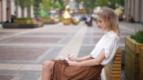 Side view of attractive focused female artist painting in sketchbook with pencil Stock Footage 227321893