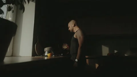 Side view of an attractive young man standing in the kitchen, drinking water and Stock Footage 252666170