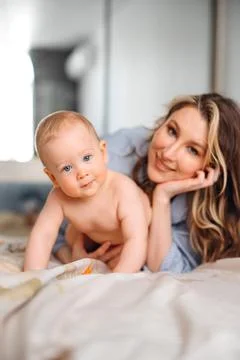 Side view of baby crawling on bed in morning light Stock Photos