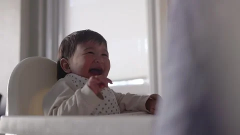 Side view of baby is sitting on a high chair and laughing Stock Footage 244827883