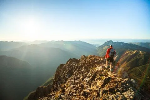 Side view of backpacker approaching mountain summit at sunset Stock Photos