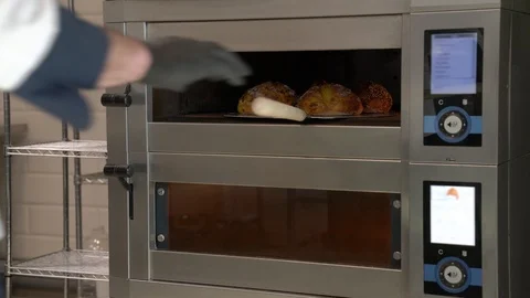 A side view of bakers hands holding a peel and taking out freshly baked bread Stock Footage 106376737
