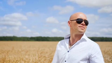 Side view of bald man going and singing in the golden wheat field. Medium shot. 스톡 동영상 113870079