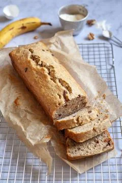 Side view of a banana bread sliced on a cooling rack with banana and flour 写真素材