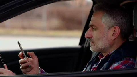 Side view of a bearded gray-haired man who is sitting behind the wheel of a Stock Footage 242610360