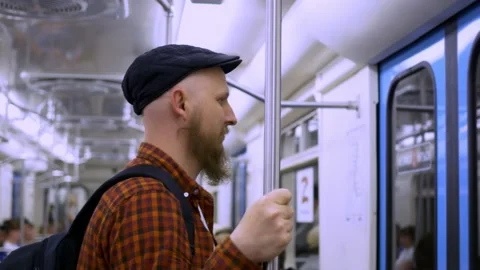 Side view of a bearded man in a cap with a backpack standing in a subway car Stock Footage 214036051