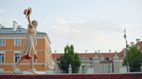 Side view beautiful blond hair woman walking along brick parapet wall outdoors Stock Footage 243861069