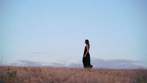 Side view of a Beautiful brunette model in long black dress going towards the Stock Footage 138342732