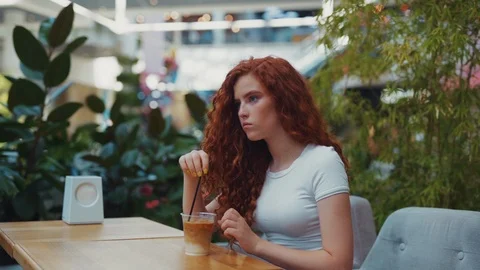 Side view of beautiful curly ginger girl sitting in café and enjoying her Video stock 114249128