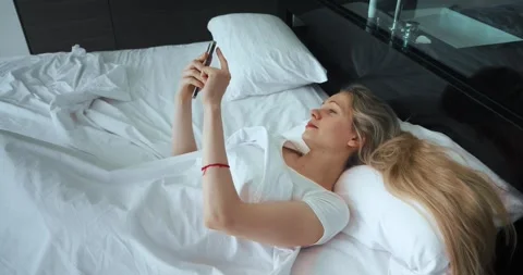 Side View Beautiful Female Using Smartphone in Bed in the Morning. Smiling 30s Stock Footage 245272555