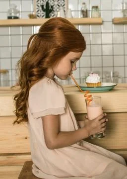 Side view of beautiful red haired drinking milkshake in cafe Stock-Fotos
