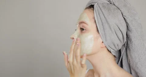Side view of beautiful young blue-eyed girl applying clay face mask Stock Footage 151260805