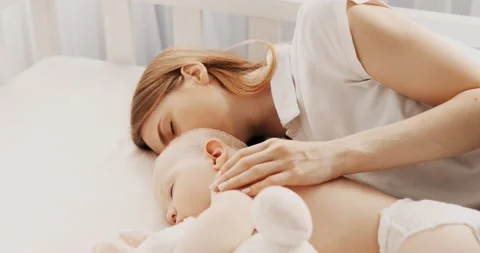Side view of a beautiful young mother and her cute little baby sleeping Stock Footage 143401617