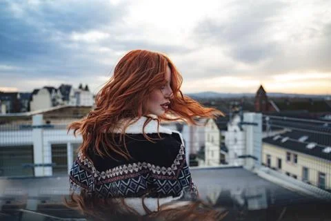 Side view of beautiful young red haired woman in evening light. Nice long wavy Stock Photos