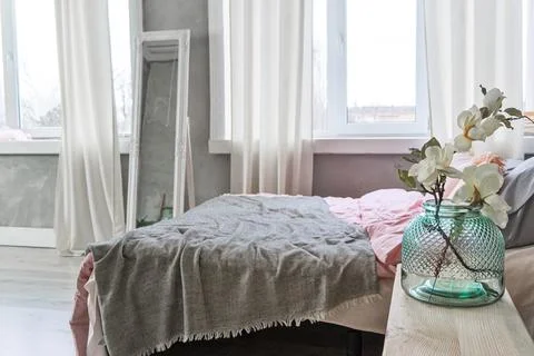 Side view on a bed with grey and pink bedding and Vase with the flowers Stock Photos