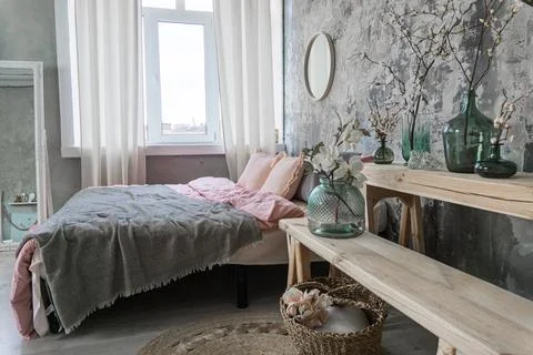 Side view on a bed with grey and pink bedding and fvases with the flowers Stock Photos