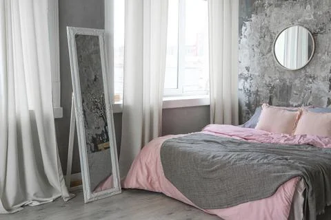 Side view on a bed with grey and pink bedding and white mirror Stock Photos