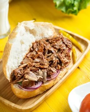 Side view of beef doner in bread with pickled green pepper on a wooden platte Stock Photos