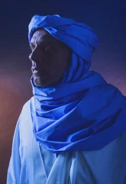 Side view of berber man in night light wearing blue turban with white robe. S Stock Photos