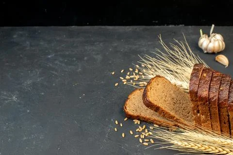 Side view of black bread slices spikes garlics on black background with fre.. 스톡 사진