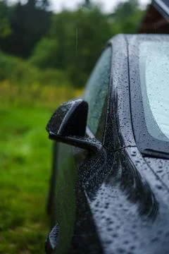 Side view of black car with raindrops by Lithuanian meadow Stock Photos