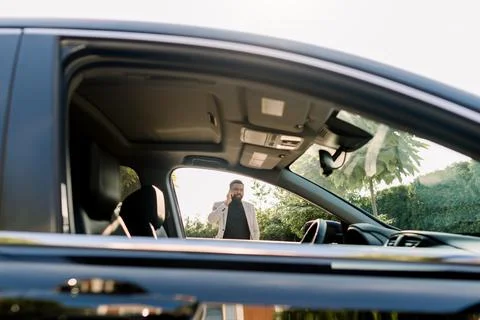 Side view of the black car window and African business man in a suit talking by Stock Photos