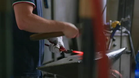 Side View of Blacksmith Hammering Hot Metal on Anvil – Forge in Foreground Stock Footage 313862887