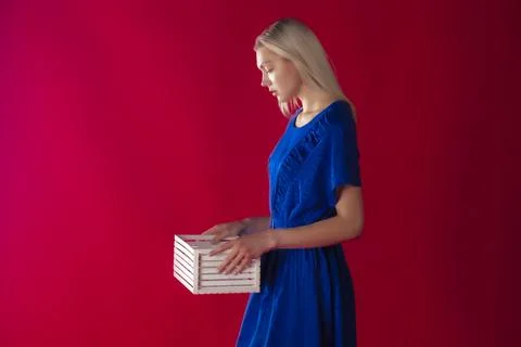 Side view blond model looking down at white mockup box on matte red backgrou Stock Photos