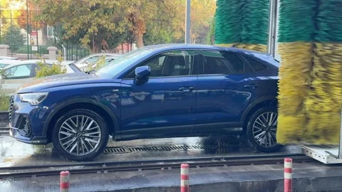 Side view of blue car being washed in an electric automatic car wash Stock Footage 289241224