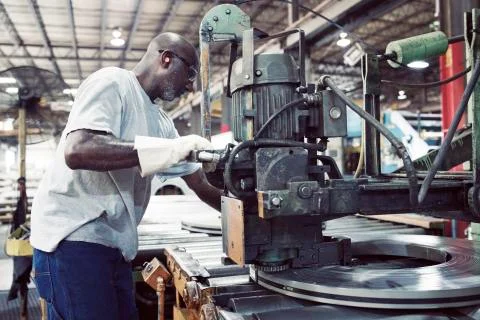 Side view of blue collar worker using machine for tying steel in factory Fotos de archivo