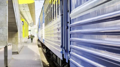 Side view of blue train car with yellow stripe stopped at station platform, Stock Footage 339866094