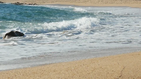Side view of blue waves breaking on sandy beach. Low angle, pan down. Stock Footage 114750507