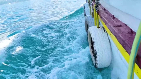 Side view of boat hull with tire fenders moving through clear blue sea Stock Footage 340533274