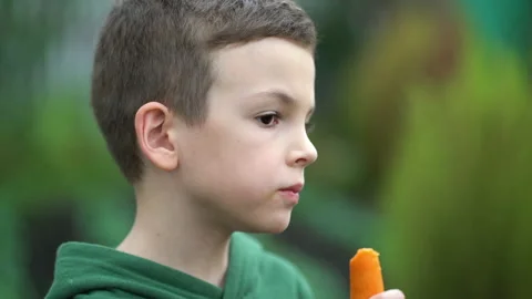 Side view boy eating raw carrots in the backyard. Stock-Footage 211182852