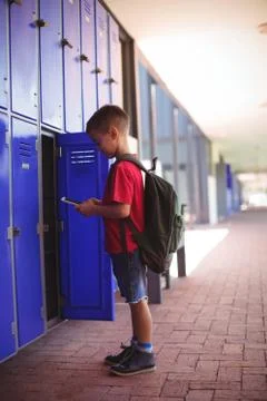 Side view of boy using mobile phone by open locker 写真素材