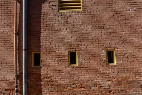 Side view of brick wall on building with small yellow windows Stock Photos
