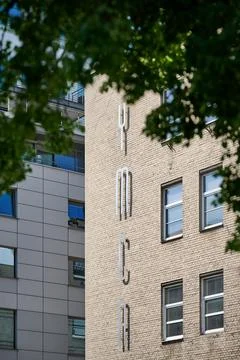 Side view of the brick YMCA building facade framed by blurred green tree leav Stock Photos