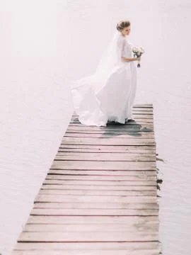 The side view of the bride with the bouquet looking on the river while standing Foto stock