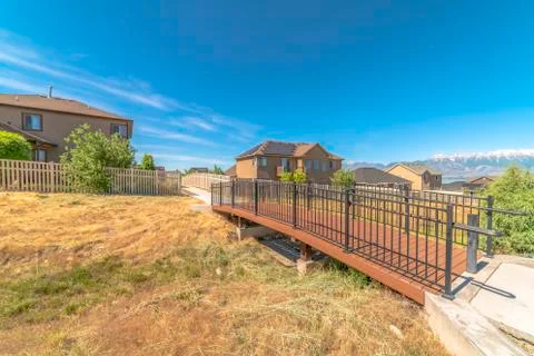 Side view of bridge that leads to pathway in the middle of homes on a sunny day Stock Photos