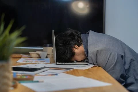 Side view of businessman heavy workload sleep on laptop at office desk with.. Stock Photos