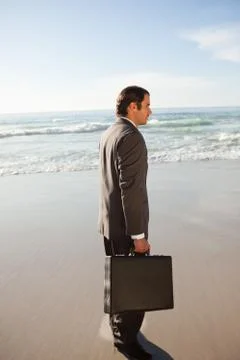 Side view of a businessman looking in front of him while standing on the beach Photos