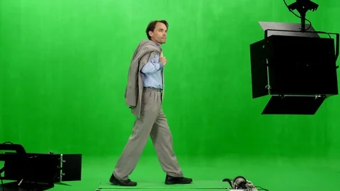 Side view of a businessman with suit jacket in hand walks in chromakey studio Stock Footage 77827784